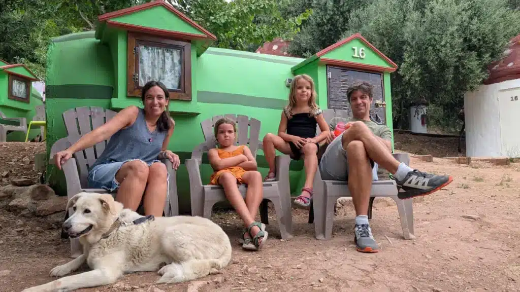 Villa Sandía: el alojamiento más original de Andalucía. 1 Familia con perro posando frente a una casa en forma de sandía en Villa Sandía, rodeados de naturaleza.