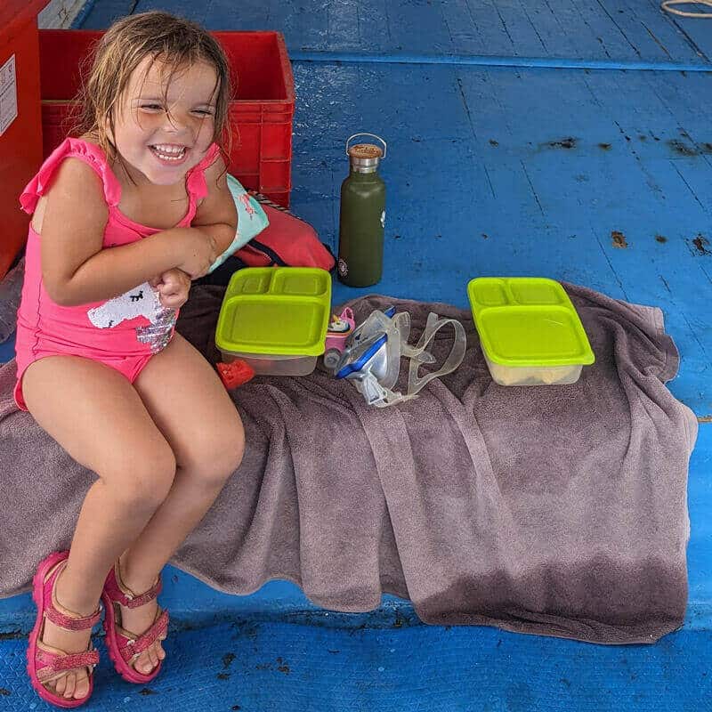 Zoe con su cajita de fruta en el barco de buceo.