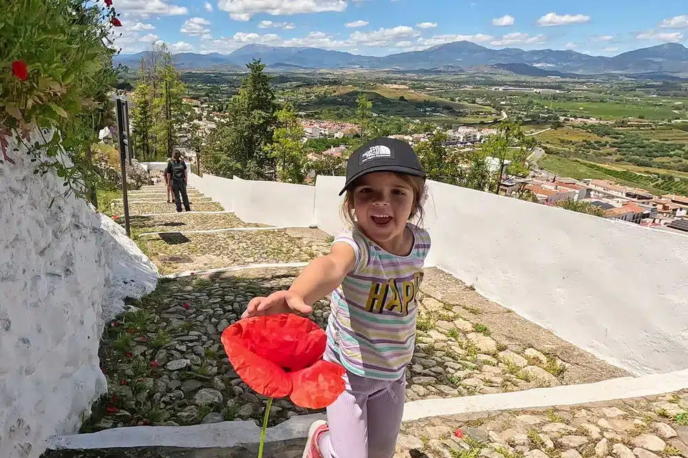 Cártama con niños: una escapada familiar cerquita de Málaga que te sorprenderá 1 Niña sonriente ofreciendo una amapola en ruta de la Ermita de Cártama con niños