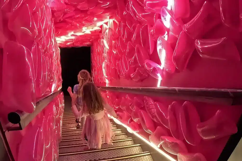 IKONO Madrid: una aventura inmersiva para despertar tu creatividad en familia 5 Pasillo rosado iluminado con niñas disfrazadas bajando las escaleras en Ikono Madrid con niños