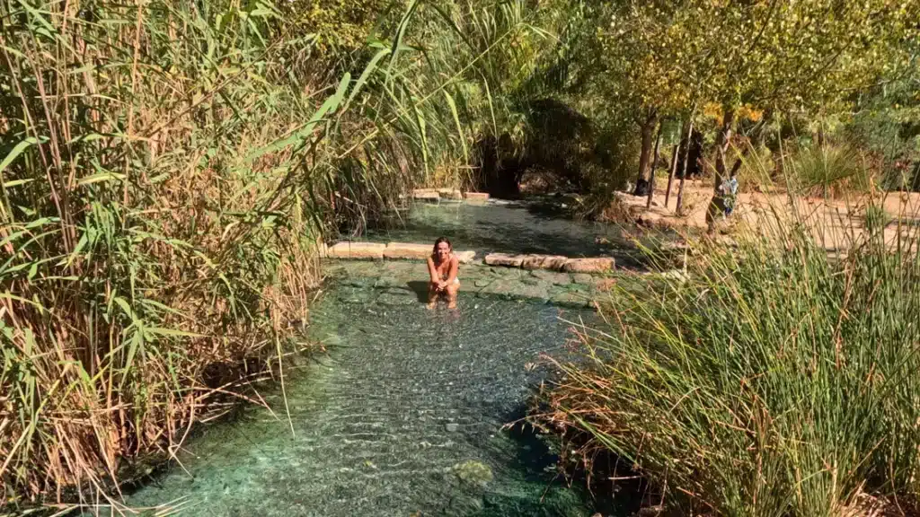 Los mejores planes acuáticos en Málaga y alrededores para refrescarte este verano 7 Mujer relajándose en uno de los pozos naturales rodeados de vegetación en los Baños de La Hedionda, Málaga.