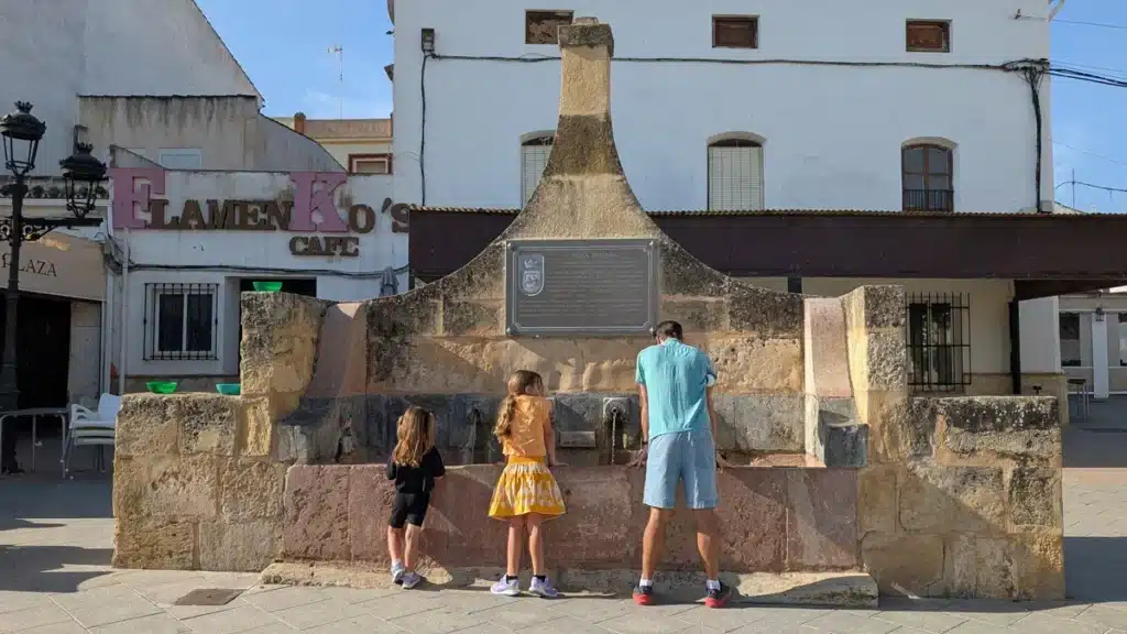 Qué ver en Fuente de Piedra: naturaleza, flamencos y planes curiosos 8 Padre y hijas contemplando el fuente histórico en la plaza de la constitución en Fuente de Piedra