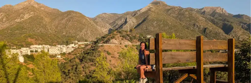 Planes para hacer en Málaga en primavera con niños 5 Lucía en el banco gigante de Istán con las montañas de la Sierra de las Nieves al fondo, un mirador icónico del pueblo blanco.