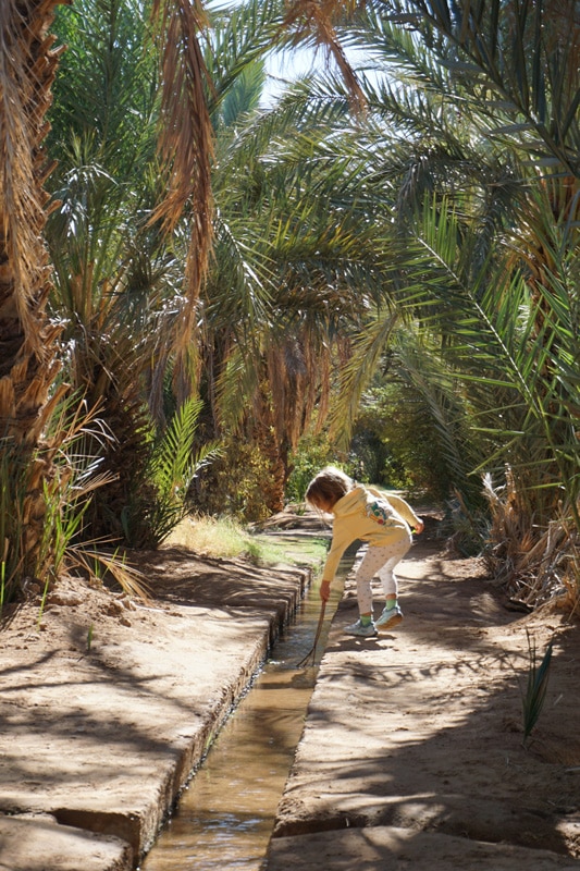niña jugando con el agua en un oasis en Marruecos